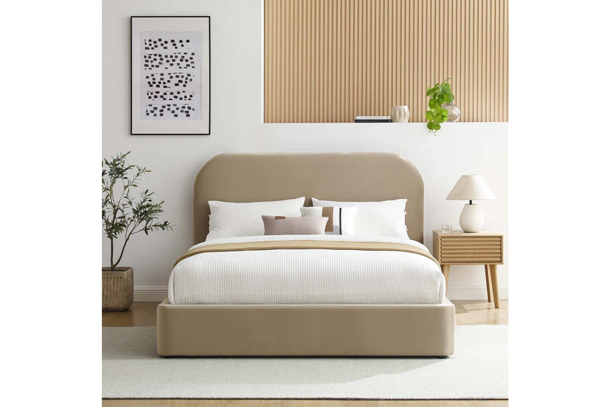 Beige upholstered bed with a rounded headboard and a wooden slatted nightstand with a white lamp.