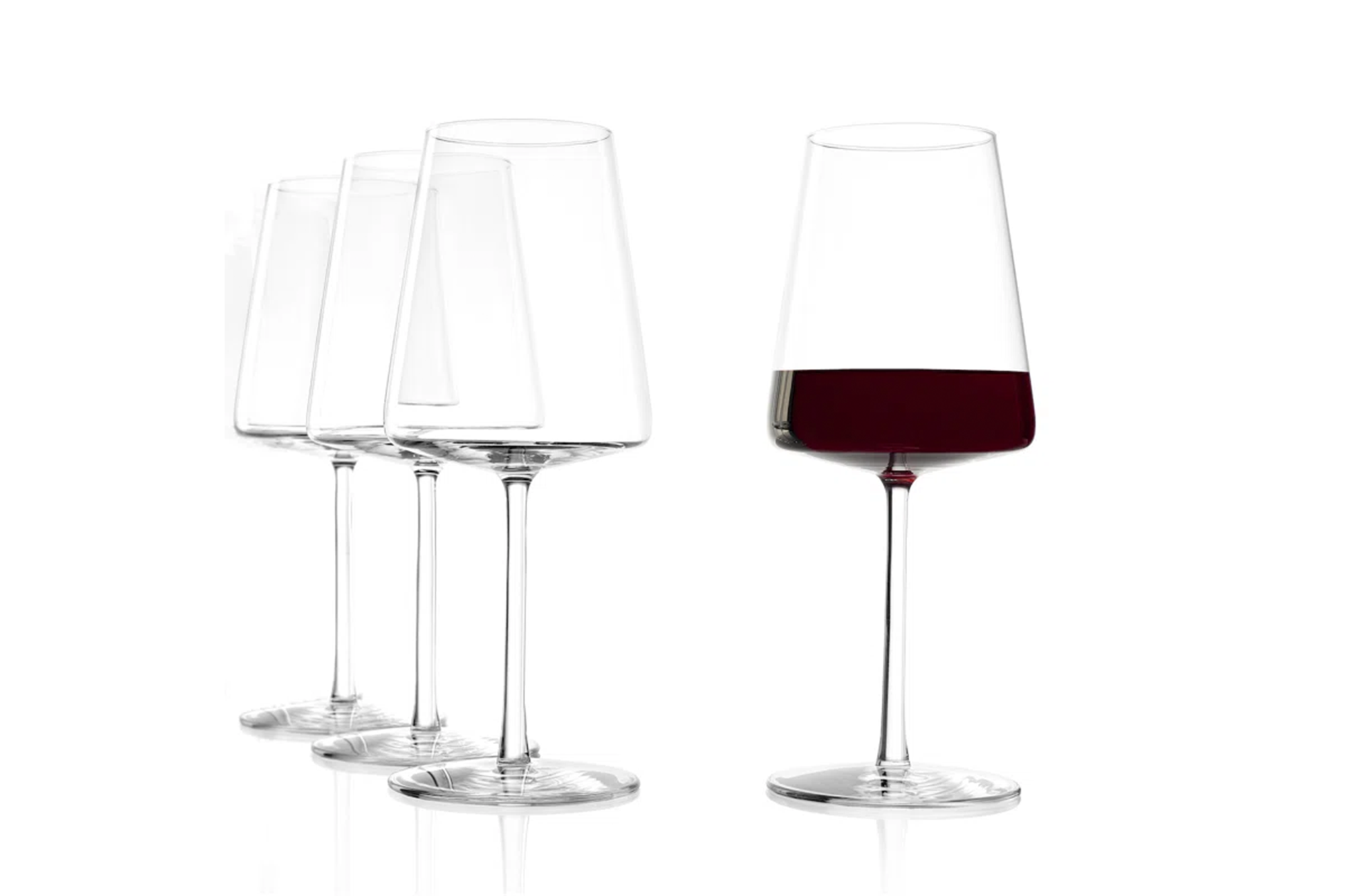 Four clear, modern wine glasses with one glass on the right half-filled with red wine.