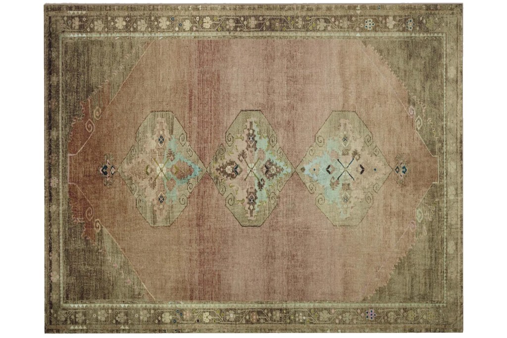 A vintage or distressed Persian rug with a rose-colored center, intricate teal, brown, and pink diamond-shaped patterns, and a dark brown border.