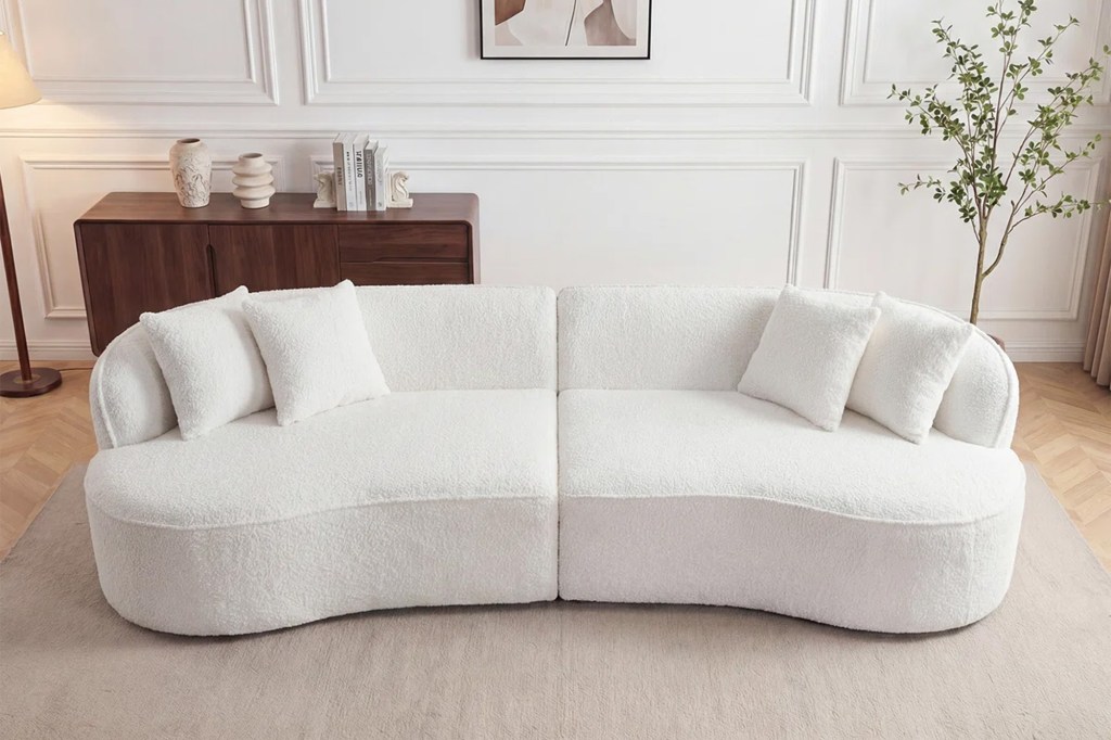 White two-piece curved sofa with white pillows.
