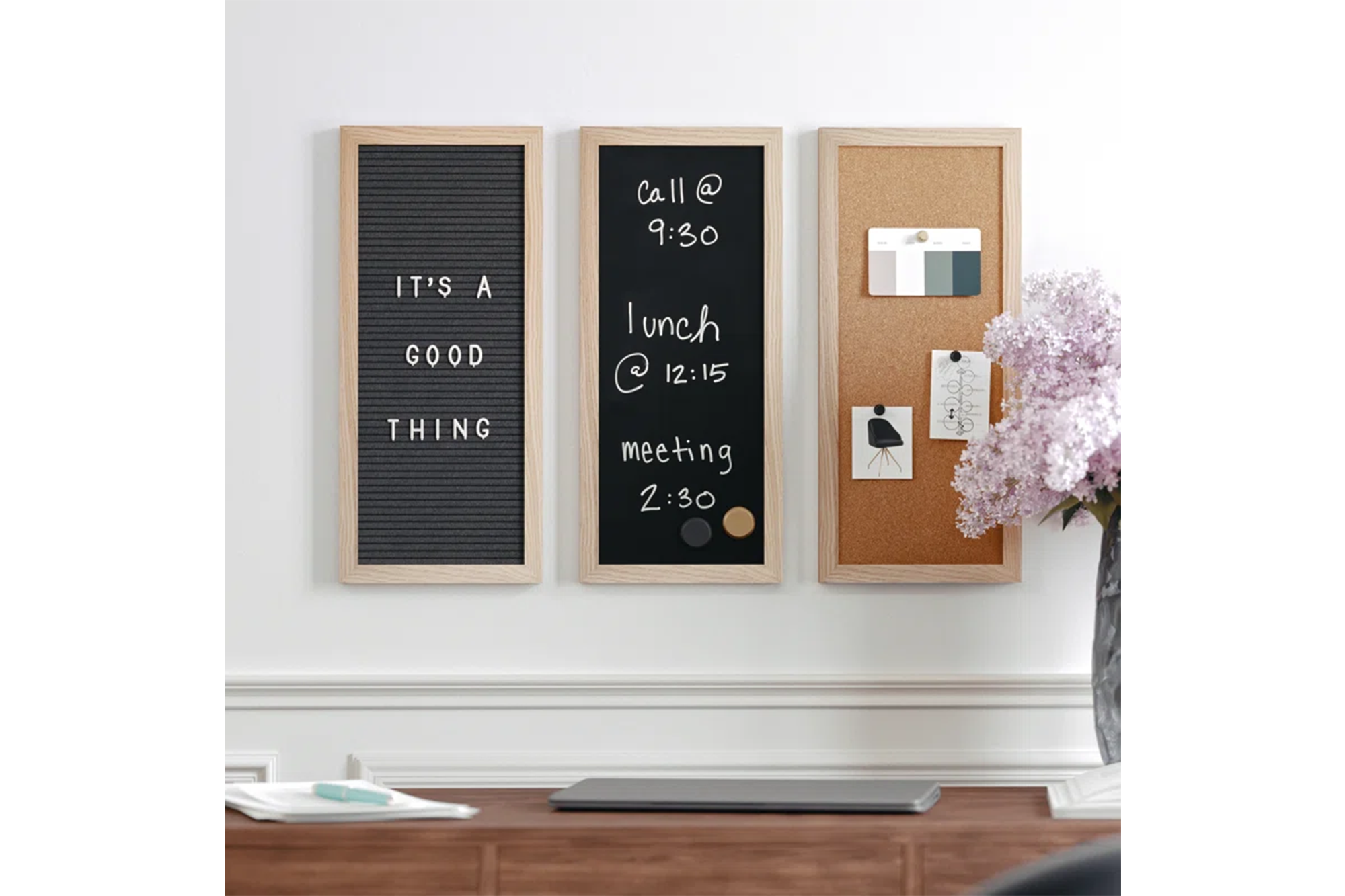 Three wooden framed boards: a black letter board, a blackboard with schedule, and a corkboard with notes, above a desk.