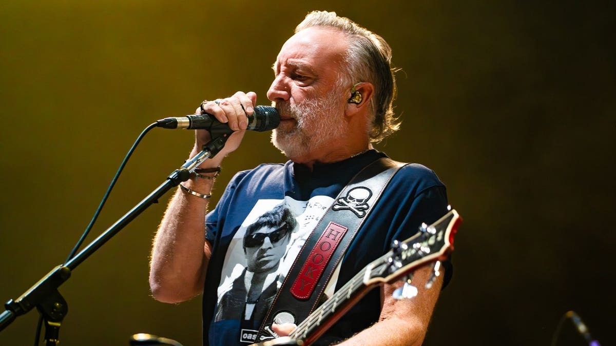 Peter Hook sings and holds a microphone