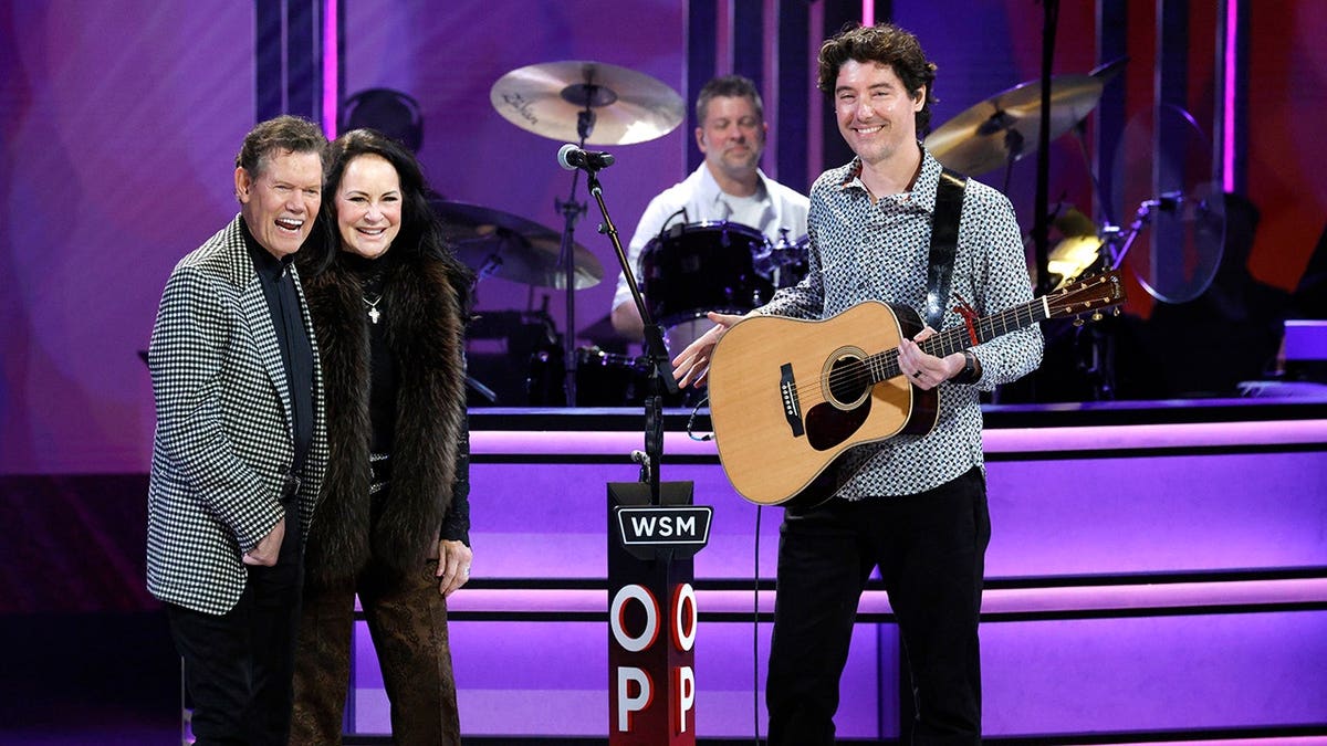 Randy Travis, Mary Travis and James Dupré standing inside the Grand Ole Opry.