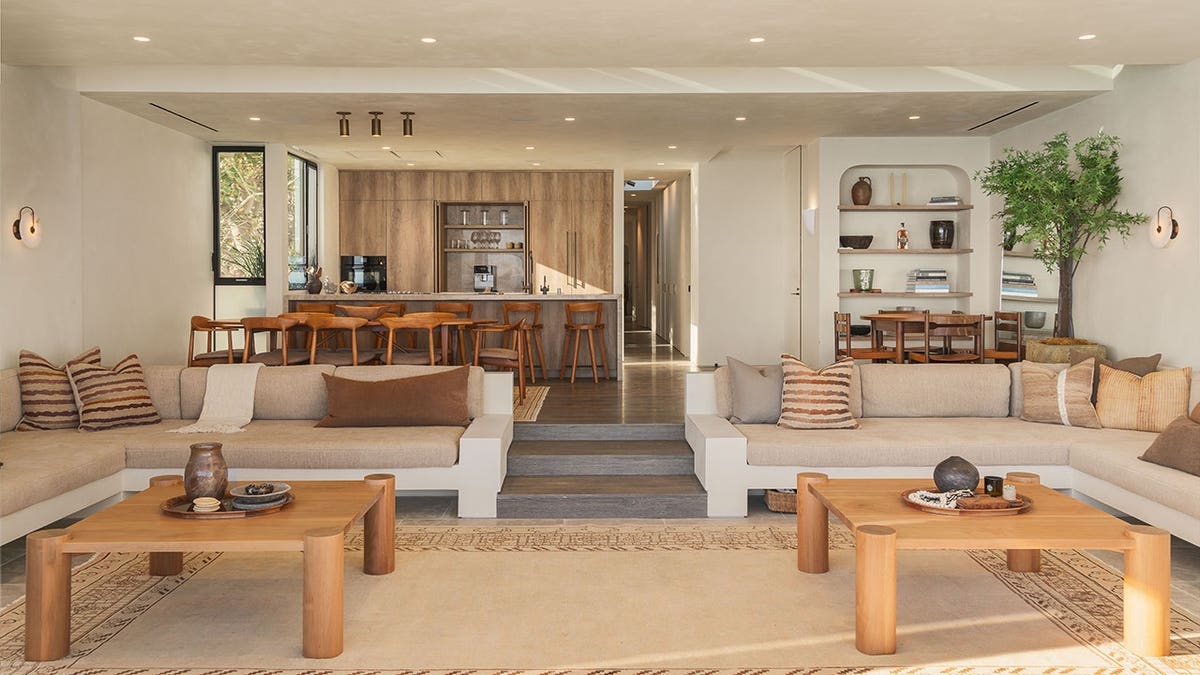 A living room with two sectional couches and wooden coffee tables.