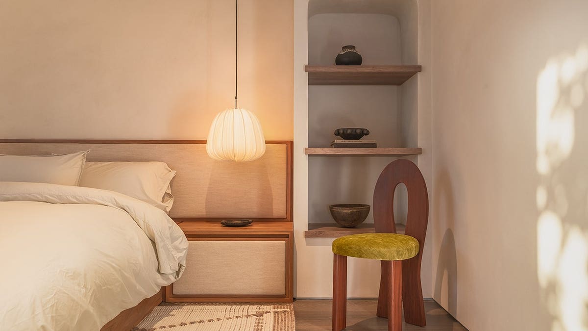 A bedroom with a big bed with white sheets and built-in shelves.