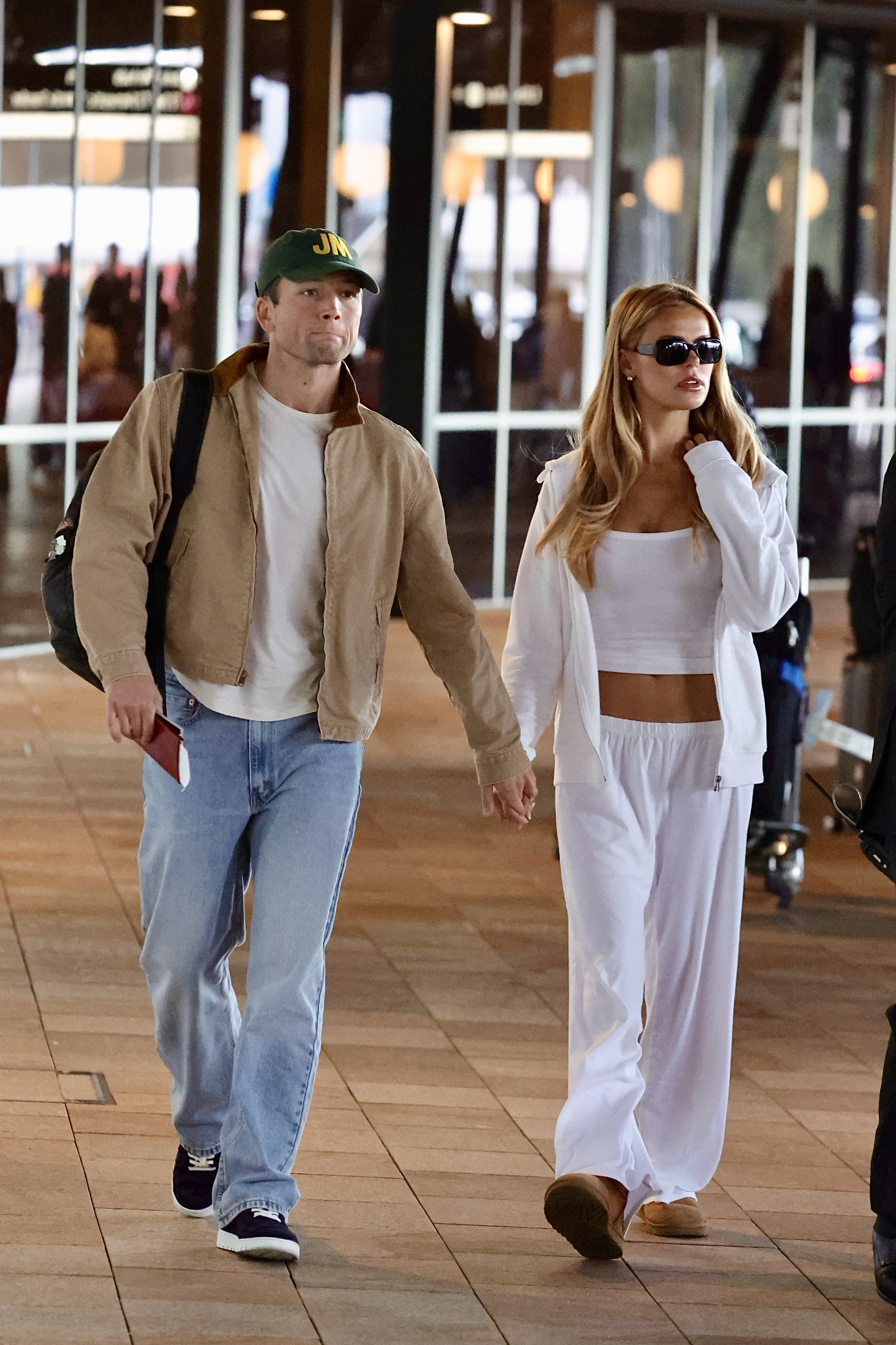 Taron Egerton and Brooks Nader hold hands while arriving in Australia.