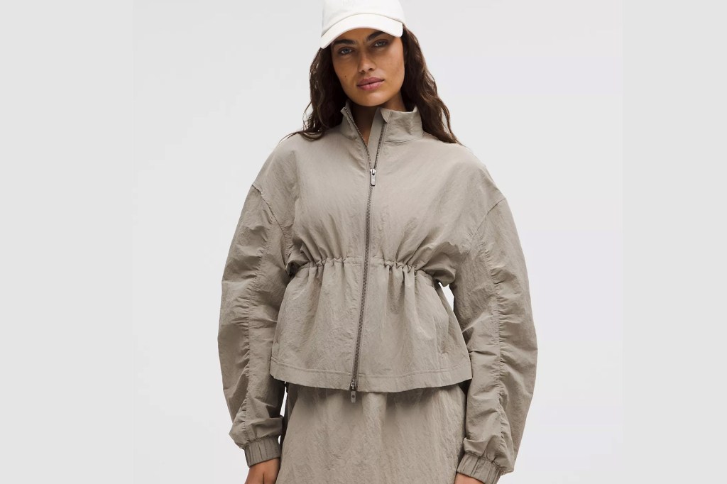 A woman wearing a beige jacket and a white cap.