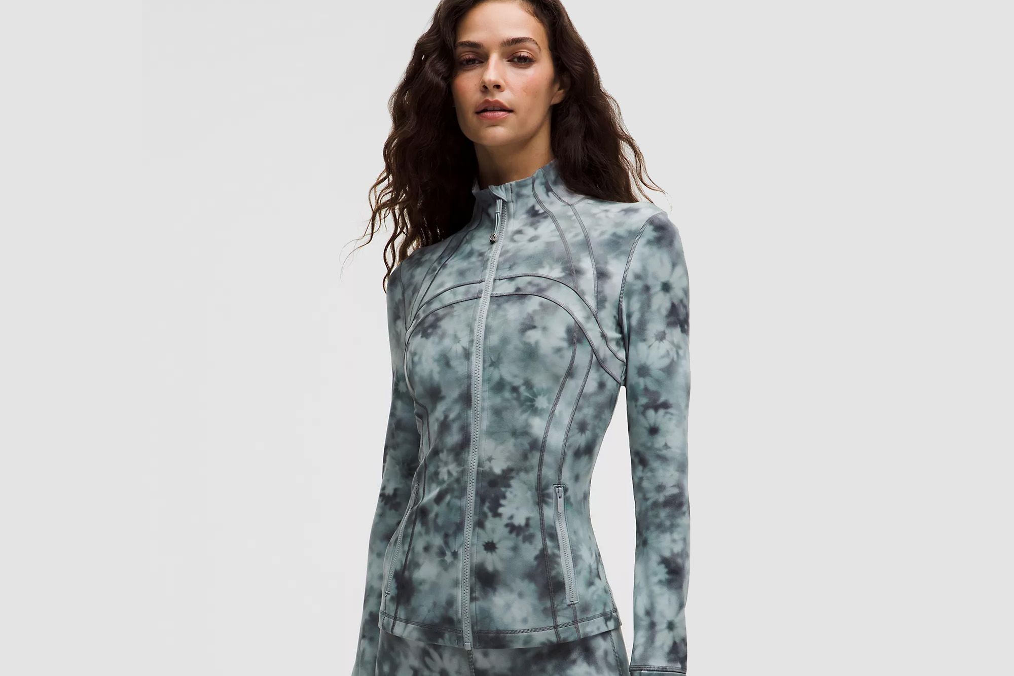 Woman in a green and black floral patterned athletic jacket.