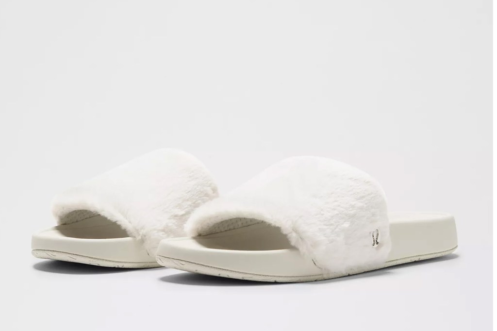 Pair of white faux fur slides with thick soles.
