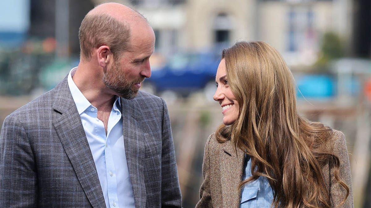 Prince William and Catherine, Princess of Wales, smiling at each other at an artisan market in Tobermory, Scotland
