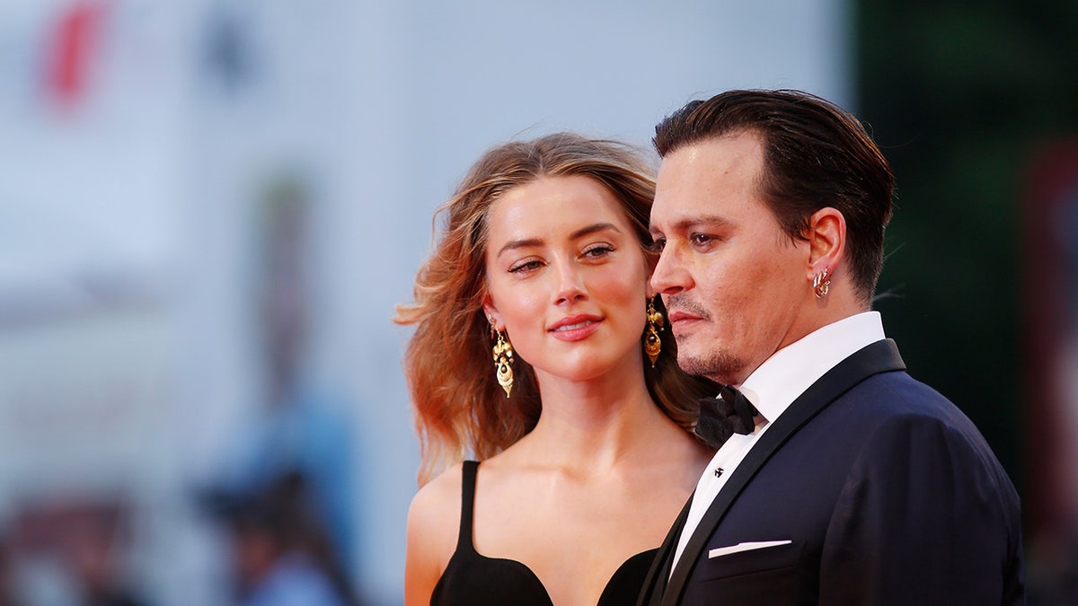Johnny Depp and Amber Heard standing together on the red carpet at a film festival.