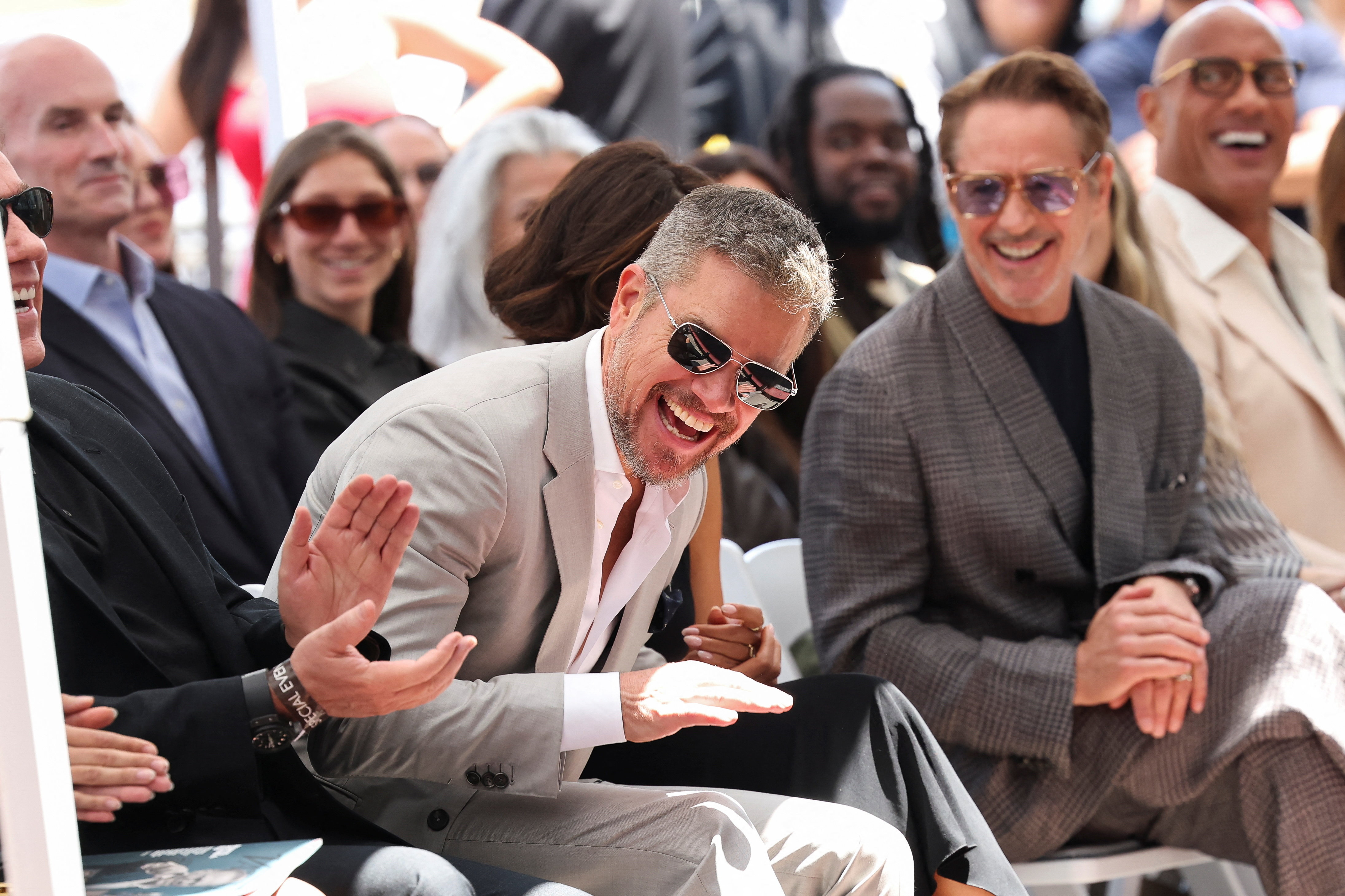 Matt Damon reacts next to Robert Downey Jr and Dwayne Johnson