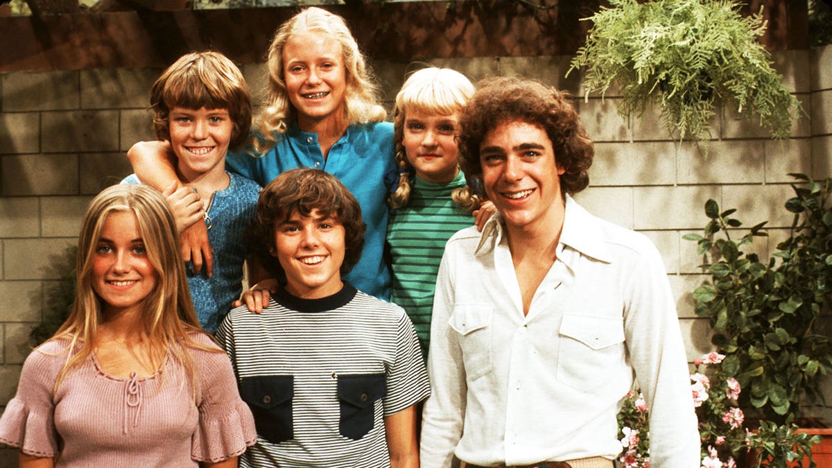 Barry Williams and Maureen McCormick smiling in a Brady Bunch kids portrait