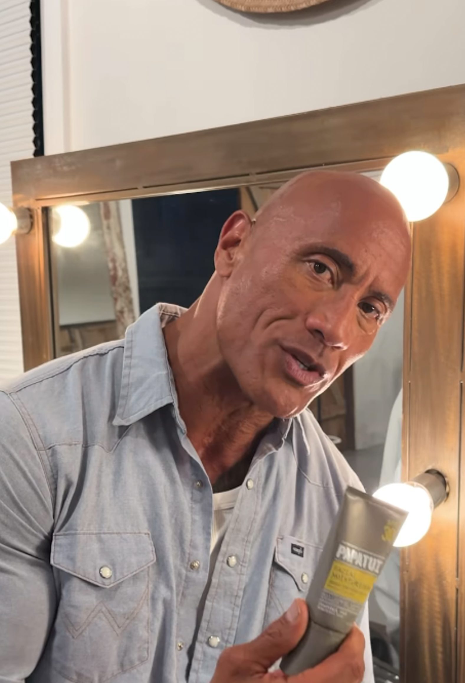 Dwayne "The Rock" Johnson holds up a tube of SPF from his brand, Papatui.