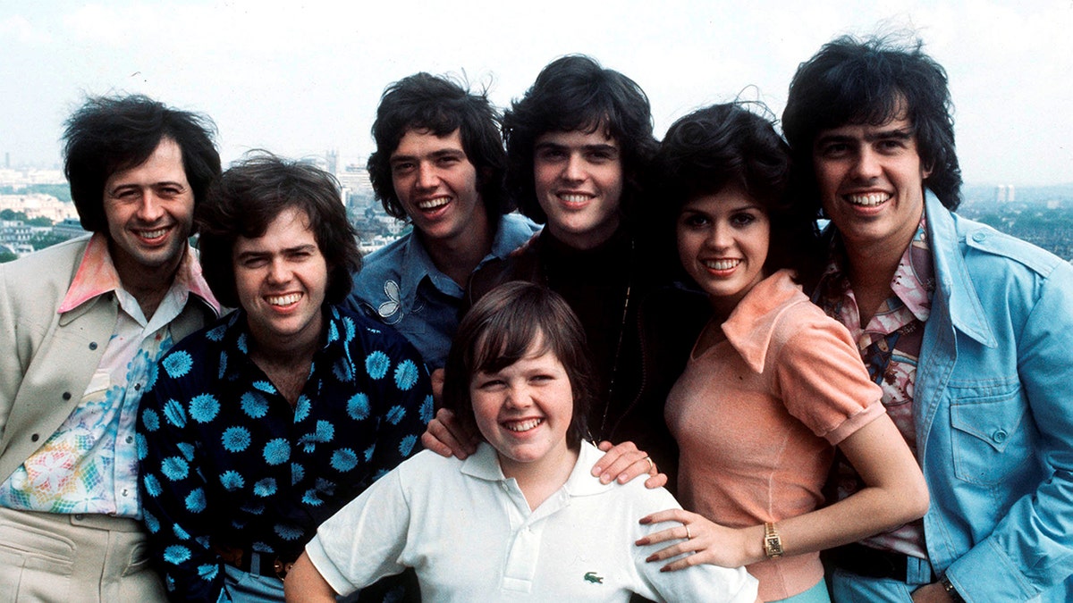 The Osmond siblings Wayne, Merrill, Jay, Jimmy, Donny, Marie and Alan Osmond posing for a group portrait.