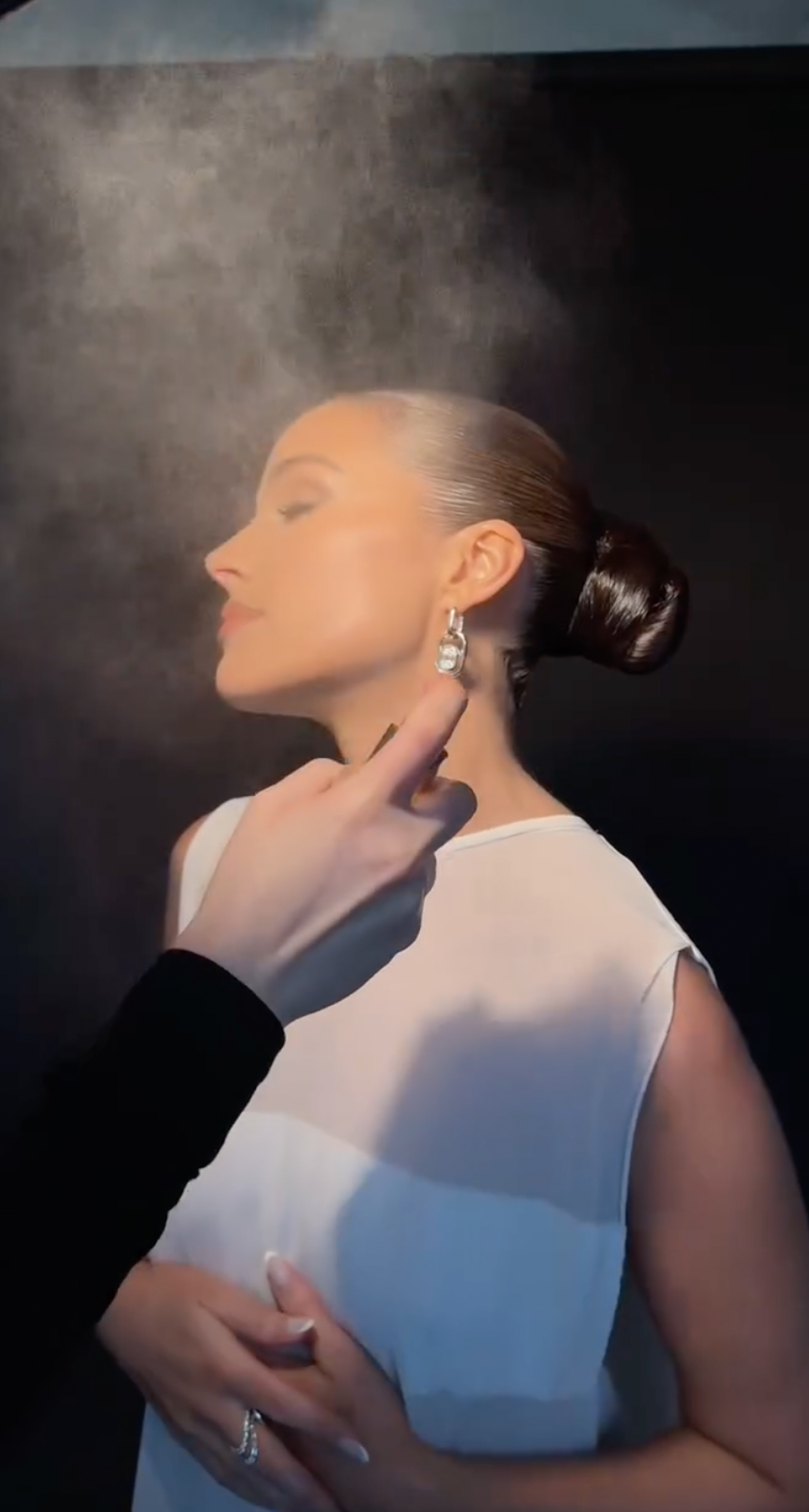 Olivia Culpo having a hydrating face mist sprayed on her face.