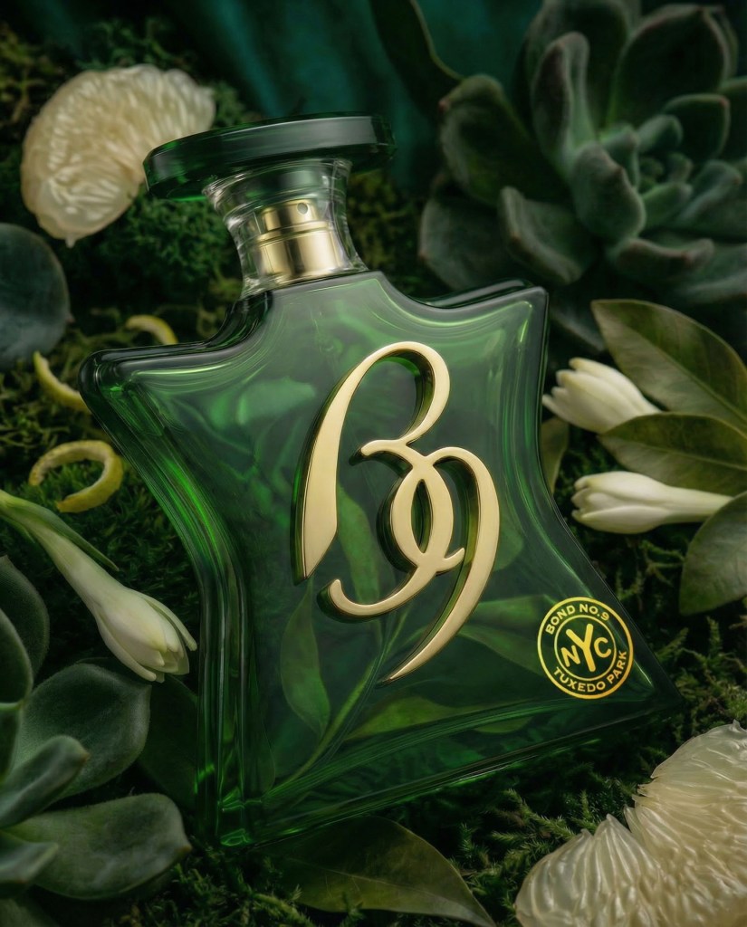 Green Bond No. 9 Tuxedo Park perfume bottle with gold "B9" emblem and "Bond No. 9 NYC Tuxedo Park" label, surrounded by plants and grapefruit segments.