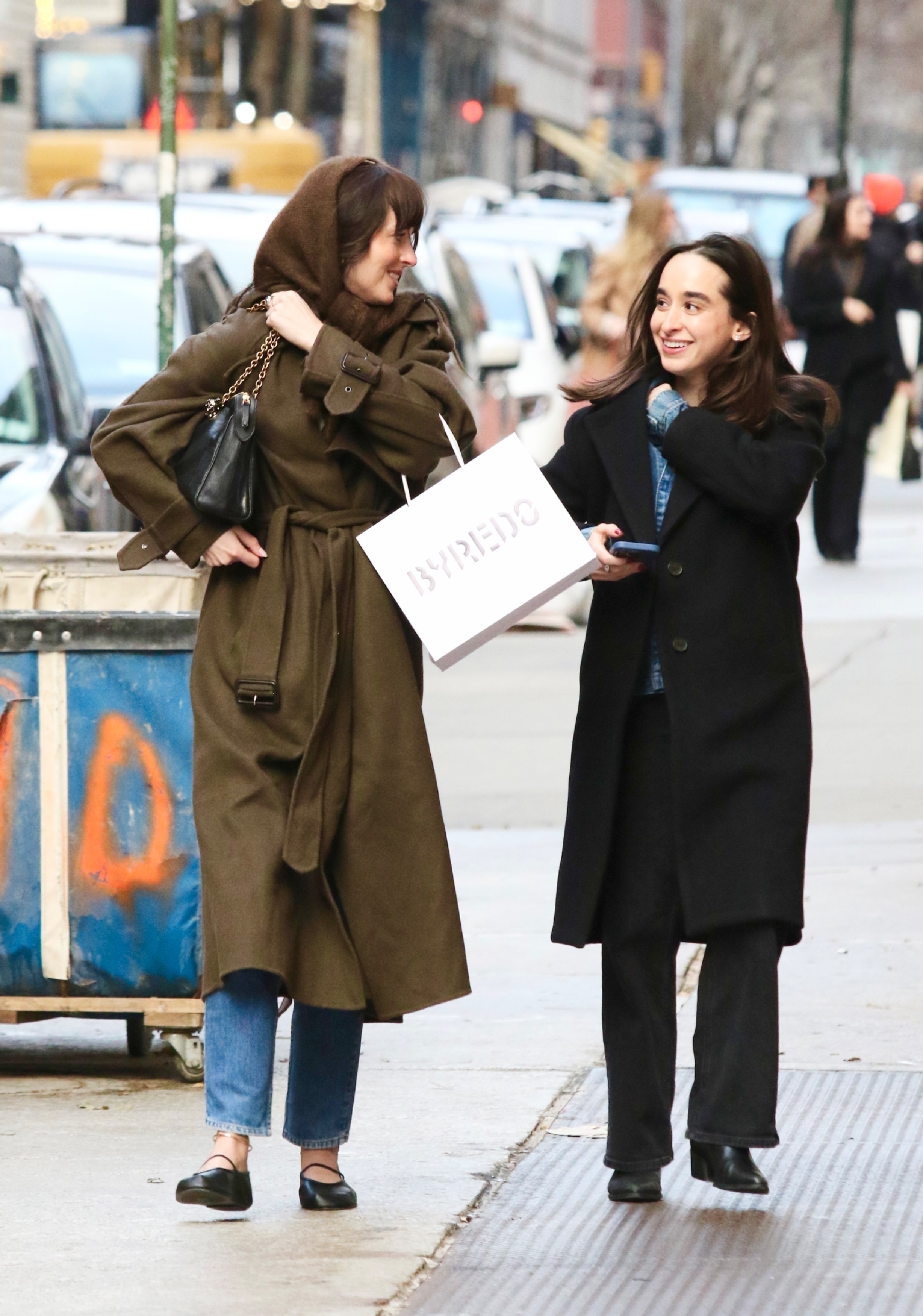 Dakota Johnson carrying a Valentino handbag and a Byredo shopping bag while walking with a friend in Manhattan.