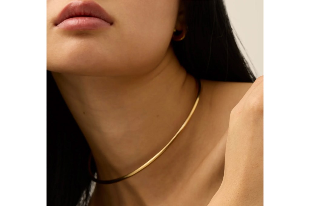 A woman wearing a gold collar necklace.