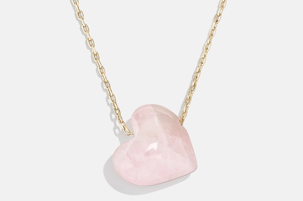 Gold chain necklace with a light pink, faceted, heart-shaped stone pendant.