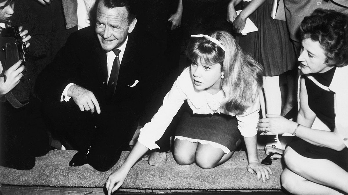 British teenage actress Hayley Mills placing her hands in the forecourt of Grauman's Chinese Theatre with her parents John Mills and Mary Mills
