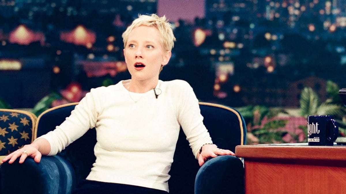 Actress Anne Heche sitting and talking with host Jay Leno on a talk show set
