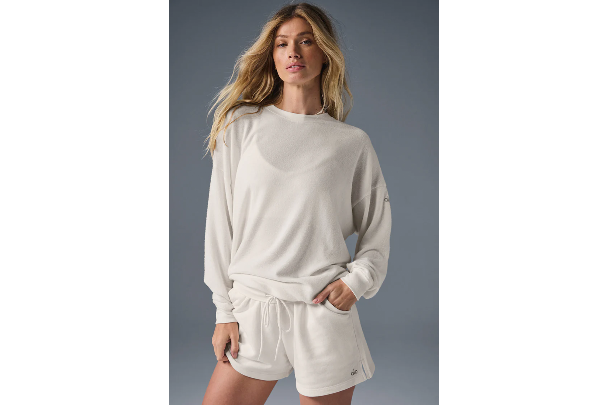 A woman modeling a long-sleeved cream top and matching shorts.