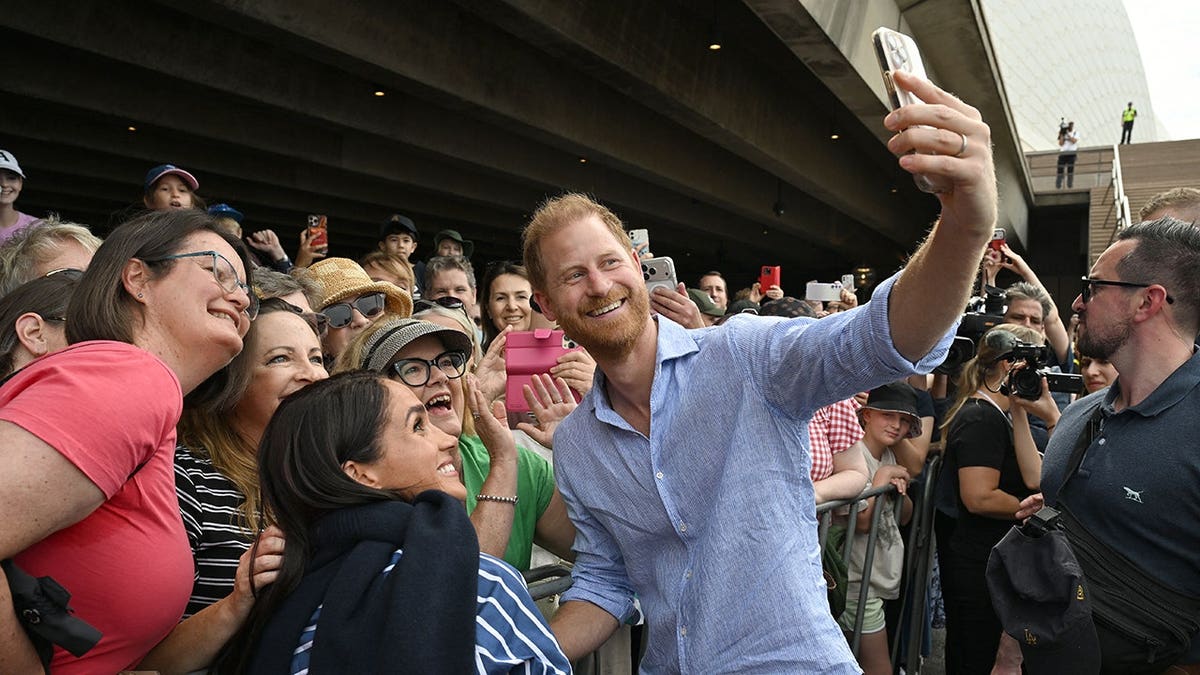 Prince Harry and Meghan Markle taking selfies with public at Sydney Opera House steps
