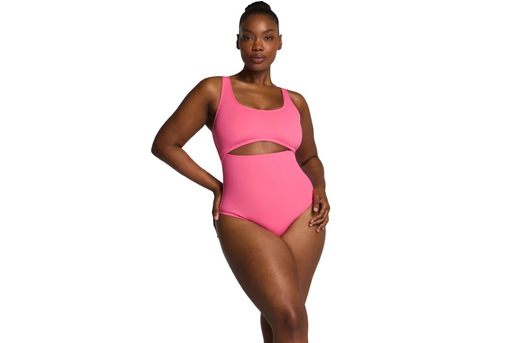 A woman in a pink one-piece swimsuit with a midriff cutout and square neck.