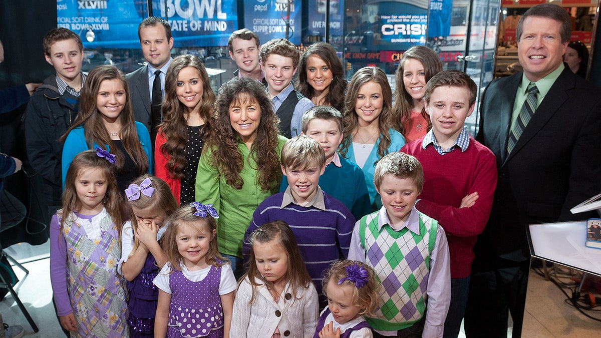 Jim Bob and Michelle Duggar with their children posing on Extra show set