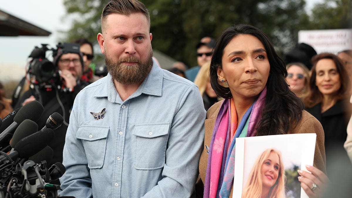 Sky Roberts and his wife Amanda Roberts holding a photo of Virginia Giuffre outside the U.S. Capitol