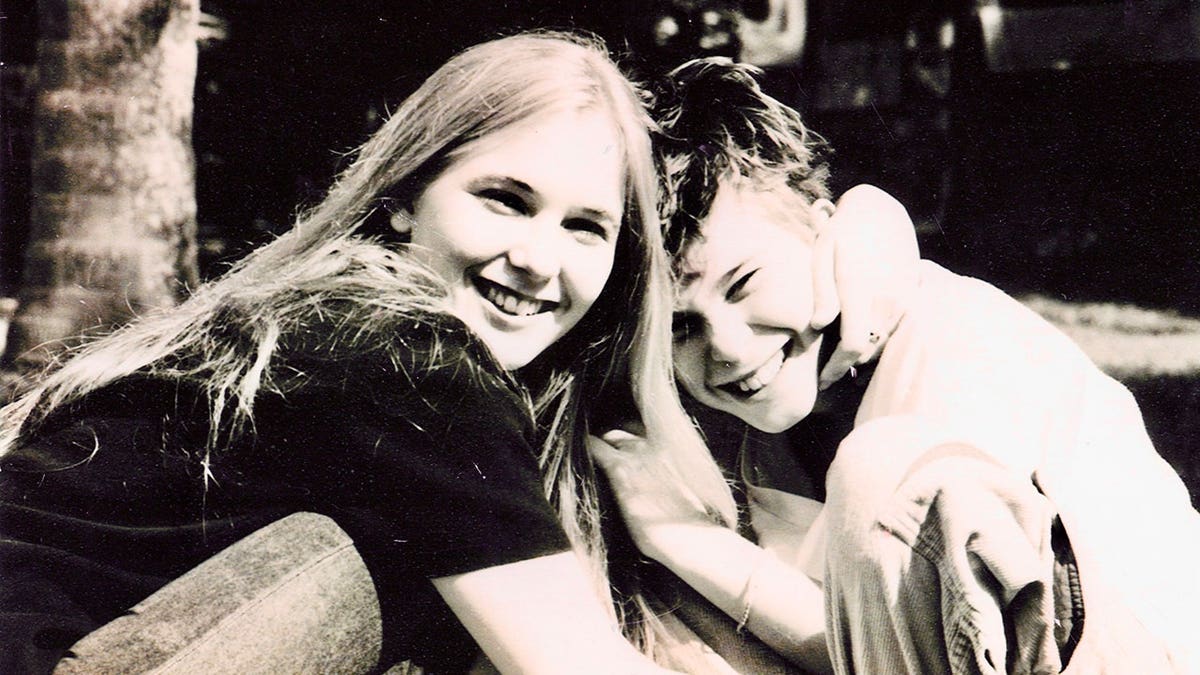 A black and white photo of Virginia Giuffre smiling with a young sibling.