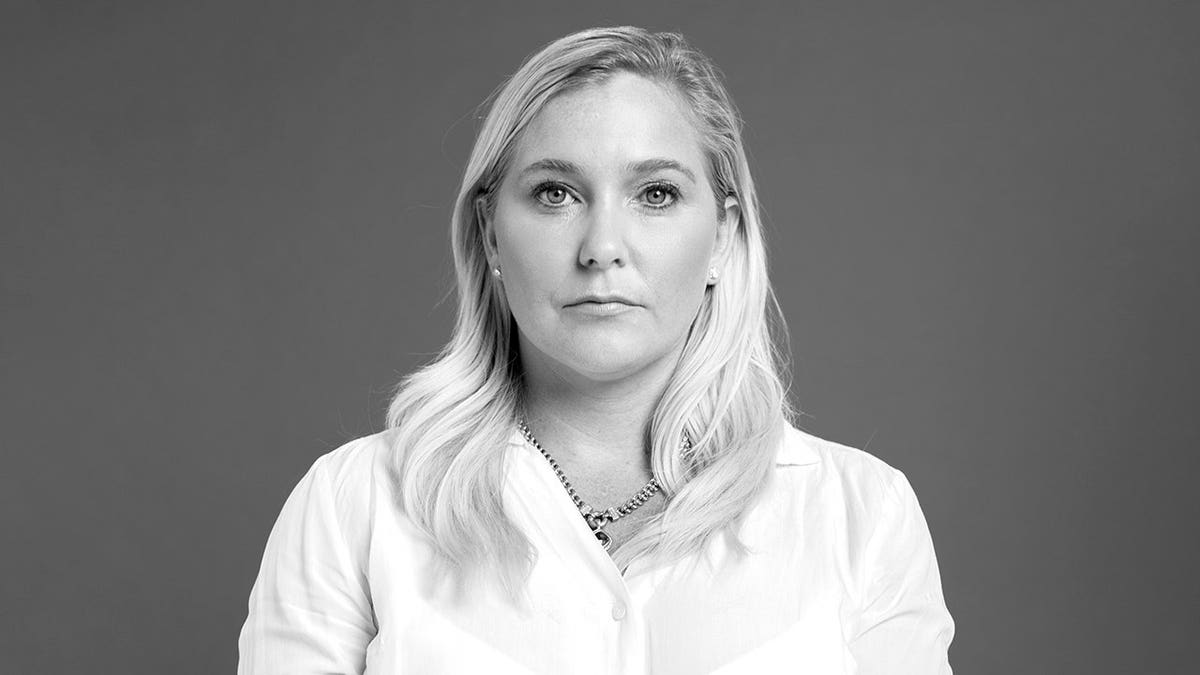 A black and white photo of Virginia Roberts Giuffre wearing a white shirt and looking somber.