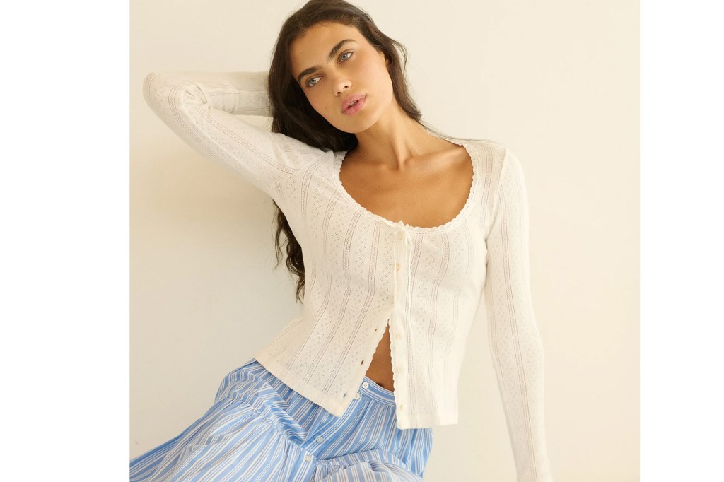 A woman wearing a white, eyelet-knit button-up top and blue and white striped skirt.