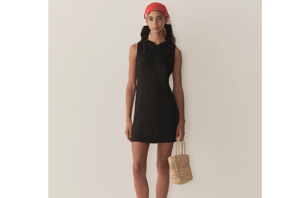 A woman wearing a black linen mini dress, a red headscarf, and carrying a woven bag.