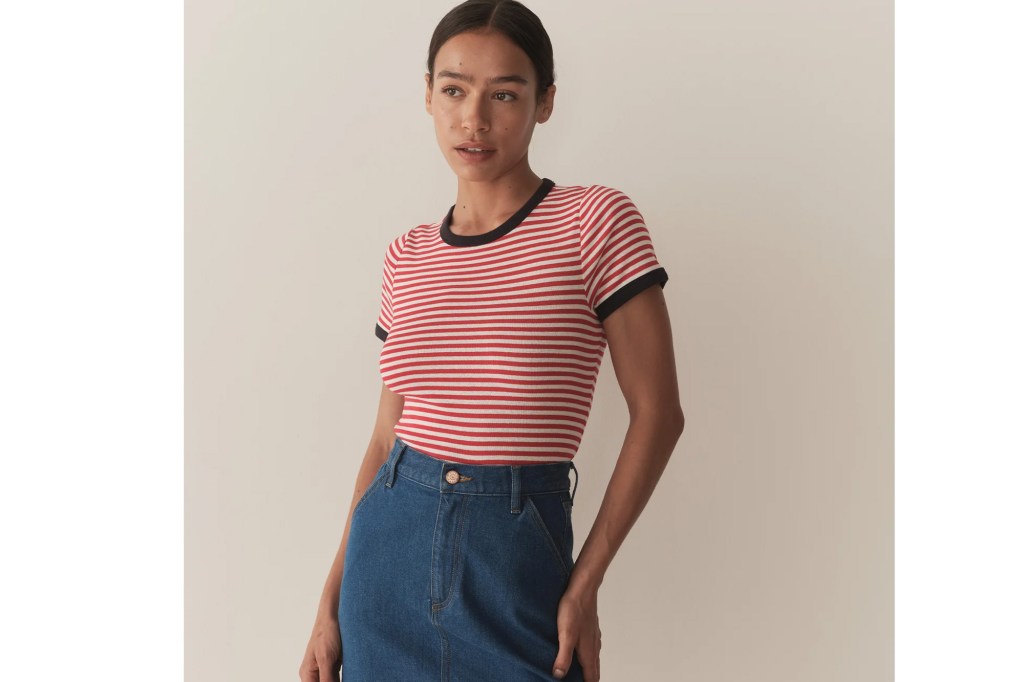 Woman wearing a red and white striped t-shirt with black trim and a denim skirt.