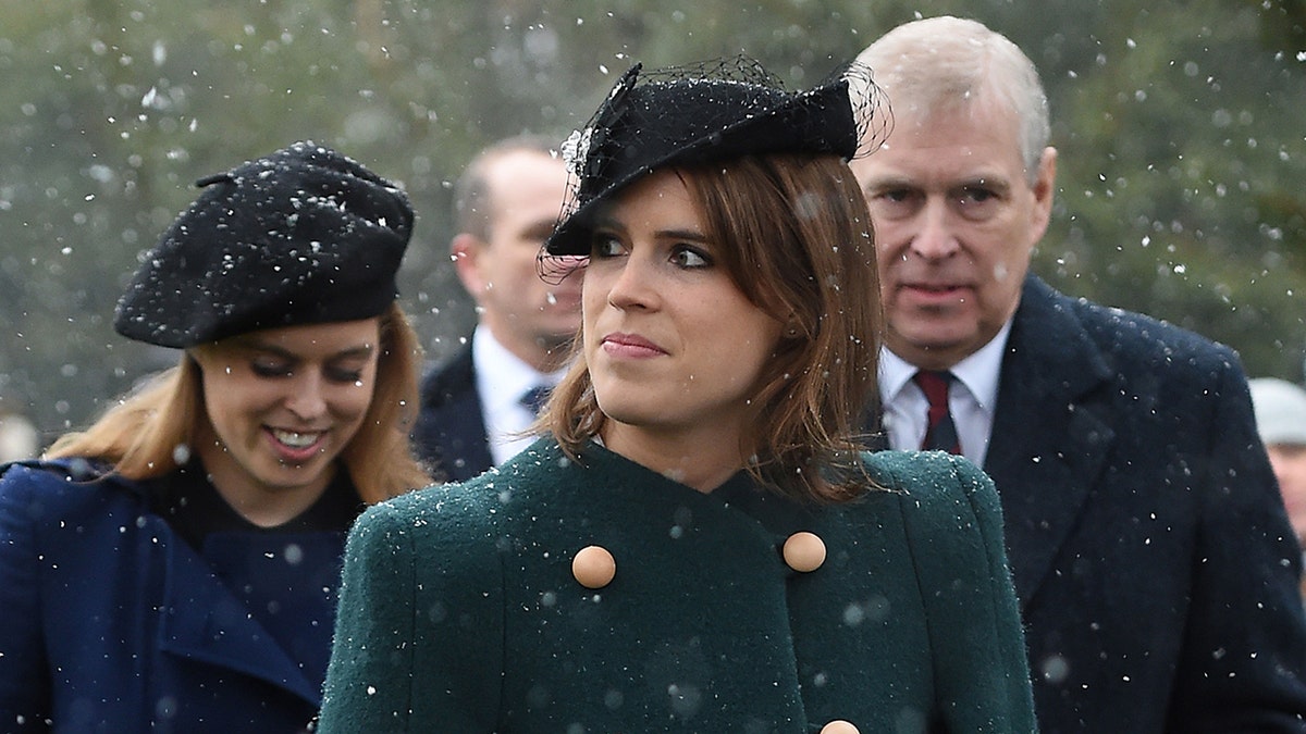 Princess Eugenie walking in the snow ahead of Princess Beatrice and the Duke of York outside a church.