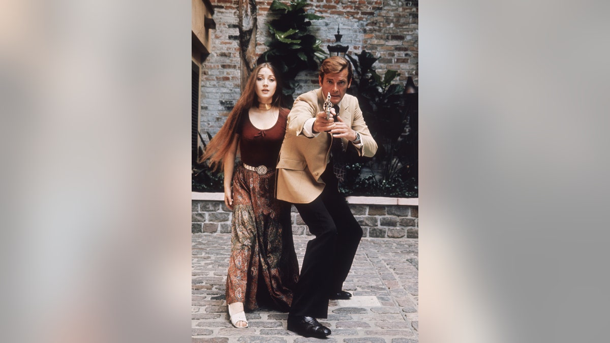 Jane Seymour as Solitaire standing next to Roger Moore as James Bond in a film scene