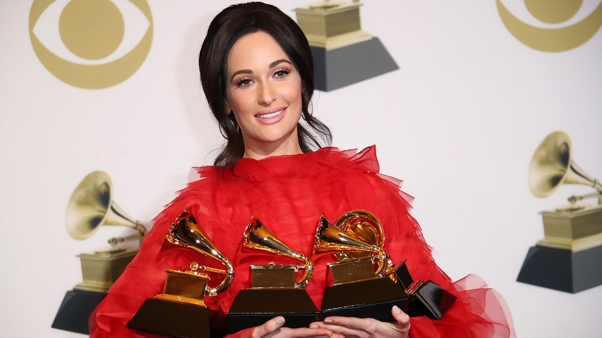 Kacey Musgraves posing with Grammy Awards in press room